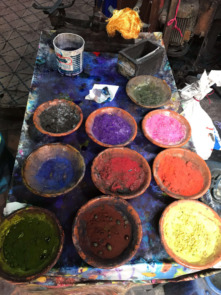 Colorful powdered dyes in clay bowls at a traditional textile workshop in Morocco