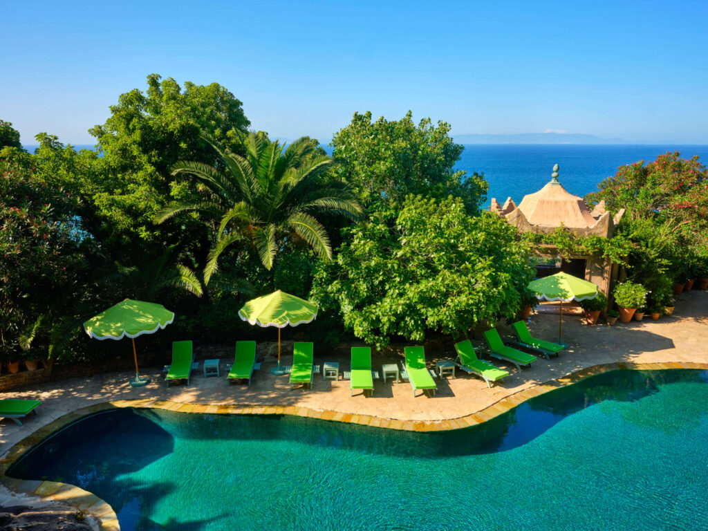 View of the lush pool area and bright green lounge chairs at Villa Mabrouka in Tangier, Morocco